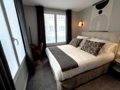 a bedroom with a bed and a large window at Hôtel Paulette Rouen Centre Cathédrale in Rouen