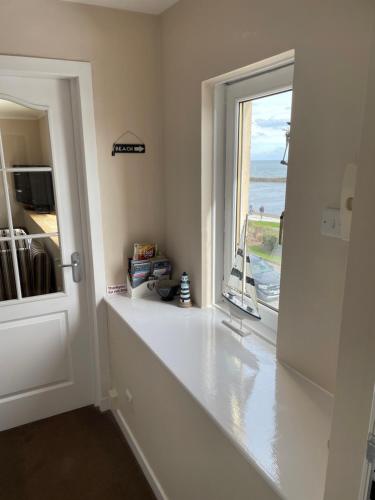 a white hallway with a window and a door at The Jewel of the Moray Firth in Lossiemouth
