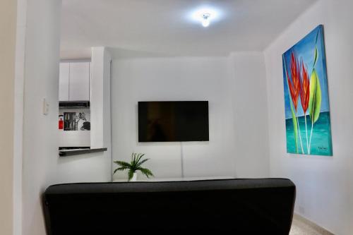 a living room with a black couch and a tv at Alojamiento espectacular, cerca al Malecón del Río, Puerta de Oro y CC Buenavista - Duchas con agua caliente in Barranquilla