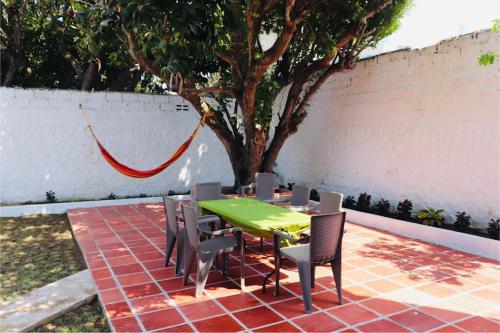 a table and chairs with a green table and a tree at Alojamiento espectacular, cerca al Malecón del Río, Puerta de Oro y CC Buenavista - Duchas con agua caliente in Barranquilla