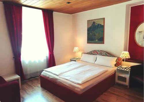 a bedroom with a large bed with red curtains at Hotel Pfaff in Triberg