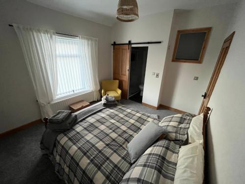 a bedroom with a bed with a plaid blanket at Railway Cottage Retreat in Blythe