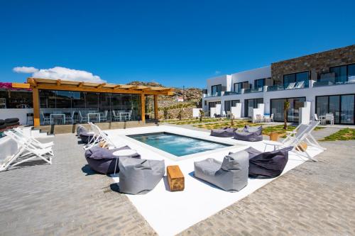 a patio with chairs and a pool and a building at Bianco a Nero Mykonos in Mýkonos City