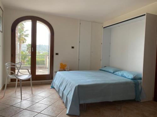 ein Schlafzimmer mit einem Bett, einem Stuhl und einem Fenster in der Unterkunft Attico Matine in Specchia