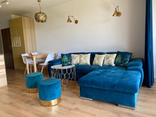 a living room with a blue couch and a table at Glemuria in Kętrzyn