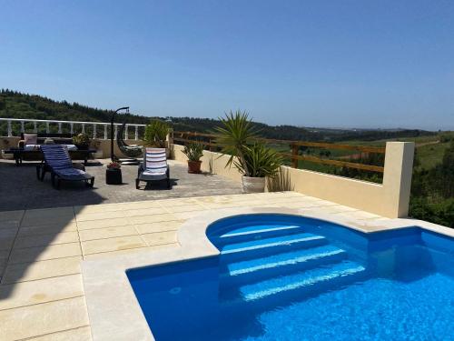 una piscina azul en un patio con sillas en Terra Luso Proche De Montejunto en Cadaval