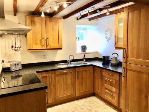 a kitchen with wooden cabinets and a sink at Limekiln Cottage in Llanasa