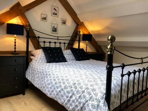 a bedroom with a black bed with a white comforter at Limekiln Cottage in Llanasa