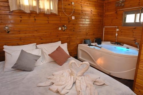 - une chambre avec un lit, une baignoire et une serviette dans l'établissement פינה במעיין, à Mishmār Hāyardin