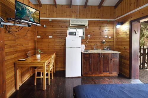 a kitchen with a white refrigerator and a wooden wall at פינה במעיין in Mishmār Hāyardin