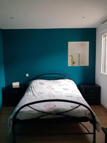 a bed in a room with a blue wall at Maison zen in Le Mans