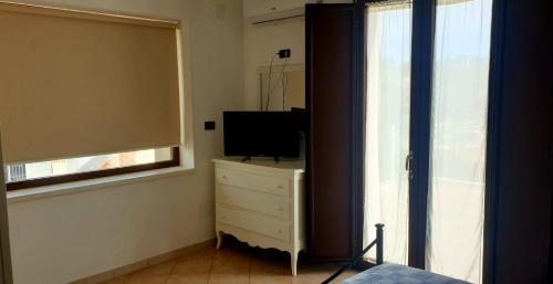 um quarto com uma cama, uma televisão e uma janela em VILLA AURORA em Ostuni