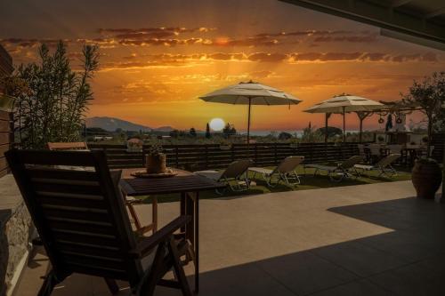un tavolo e sedie con tramonto sullo sfondo di Magnolia Homes Zakynthos a Città di Zante