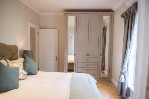 a bedroom with a bed and a closet and a mirror at Maison Des Huguenots Le Roux in Franschhoek