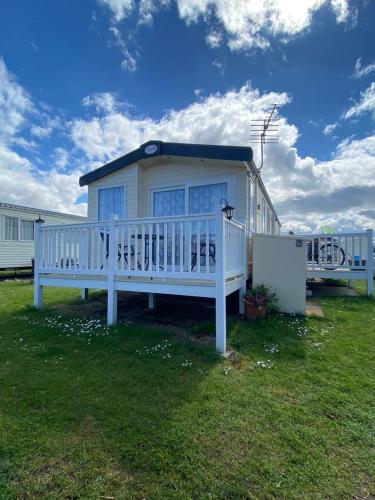 Seton Sands Haven Holiday Park - Platinum Caravan في Prestonpans: منزل أبيض كبير مع شرفة على العشب