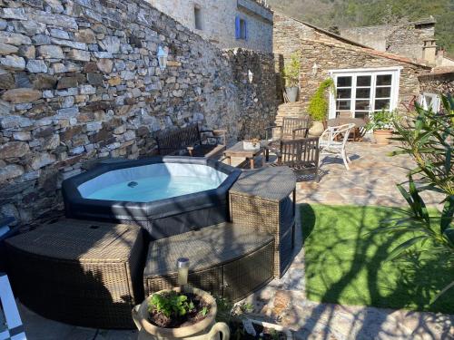 a backyard with a hot tub and a stone wall at Les Terrasses in Cabrespine