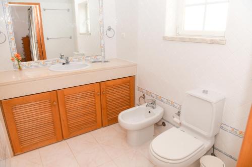 Un baño con inodoro, lavabo y espejo. en Casa América, en Casal da Lagoa Seca