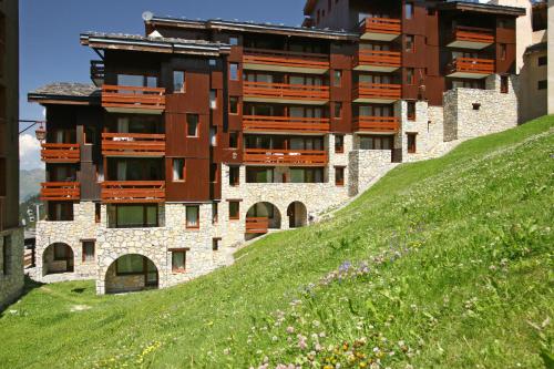un grand bâtiment au sommet d'une colline herbeuse dans l'établissement Résidence Pierre & Vacances Emeraude, à Belle Plagne