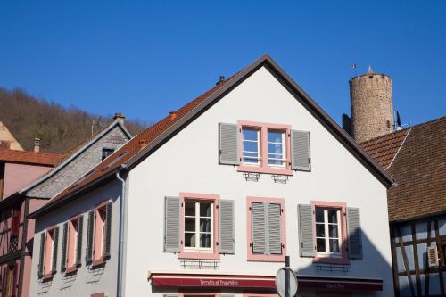 a white house with pink shutters on a street at Chambres Chez Laurence in Kaysersberg