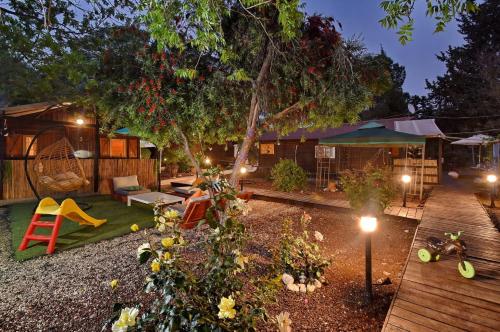 a backyard with a playground and a house with lights at פינה במעיין in Mishmār Hāyardin