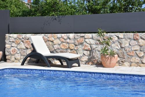 a white chair sitting next to a swimming pool at Vila Palma in Vrbnik