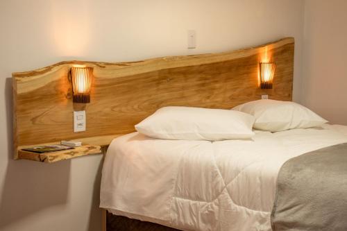 a bedroom with a large bed with a wooden headboard at Refúgio Fortal in Cambara do Sul