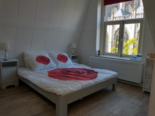 ein Bett mit roten Rosen und einem Fenster in der Unterkunft Voorstraat-Havenzicht 2de in Dordrecht