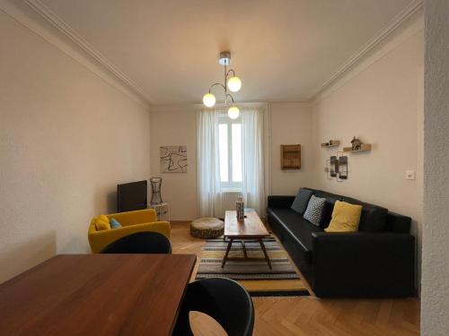 a living room with a black couch and a table at Appartement LUNA avec parking couvert privé in Le Locle