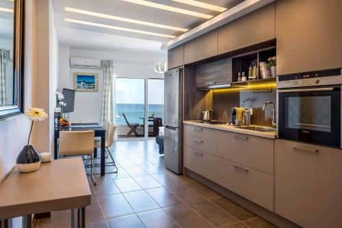 イエラペトラにあるKyma Crete Beachfrontのステンレス製の電化製品が備わるキッチン、海の景色を望むバルコニーが付いています。
