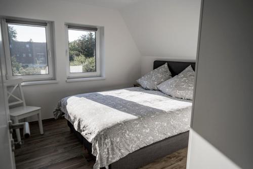 a bedroom with a bed and two windows at Hohwaii Waikiki in Hohwacht