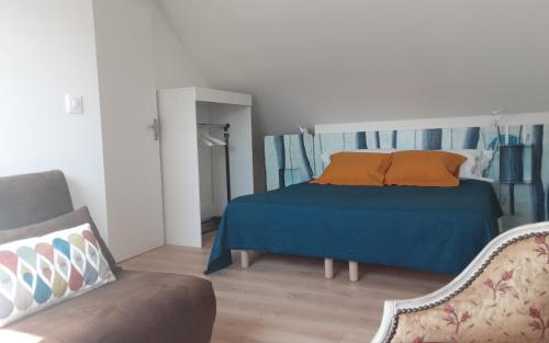 - une chambre avec un lit doté d'oreillers orange et d'un canapé dans l'établissement Kerlobek l'id île, à Groix