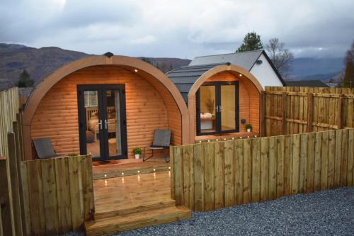 a wooden cabin with a fence in front of it at Apex Studio Pod & Jacuzzi Bath in Fort William