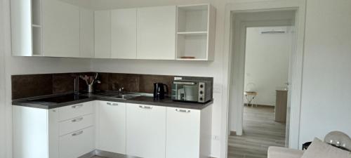 a white kitchen with a sink and a microwave at Riccio di Mare in Lacona