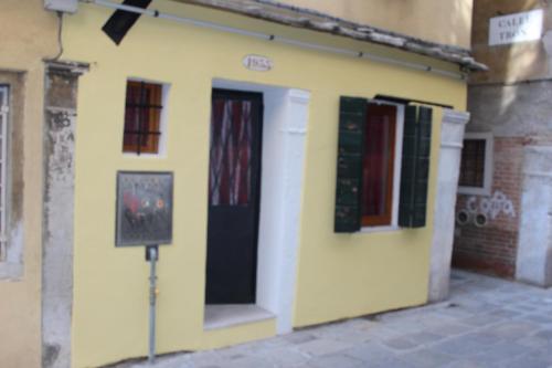 żółty budynek z czarnymi drzwiami i oknami w obiekcie CHIARA HOUSE VENICE w Wenecji