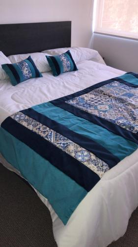 a bed with blue and white sheets and pillows at Departamento en El Tabo in El Tabo