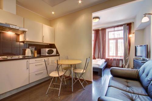 a kitchen and a living room with a table and a couch at STN Apartments on Nevsky 60 in Saint Petersburg