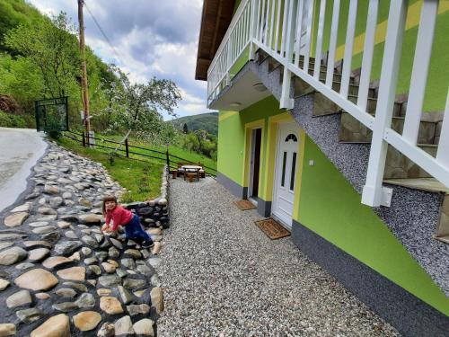 a child sitting on the rocks next to a building at Apartmani Vila na Drini in Foča