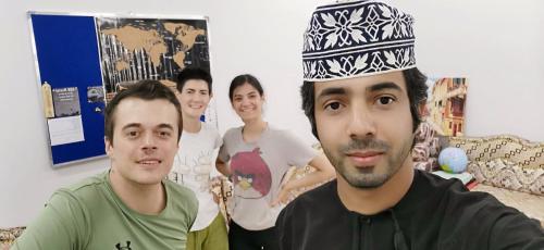 a group of people standing around a man wearing a hat at 228Hostel in Al Ḩamrāʼ