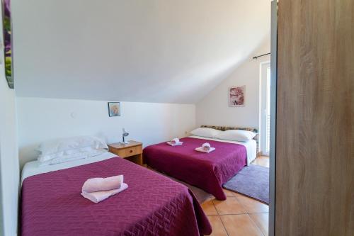 a bedroom with two beds with pink sheets and towels at Apartment Nada in Petrcane