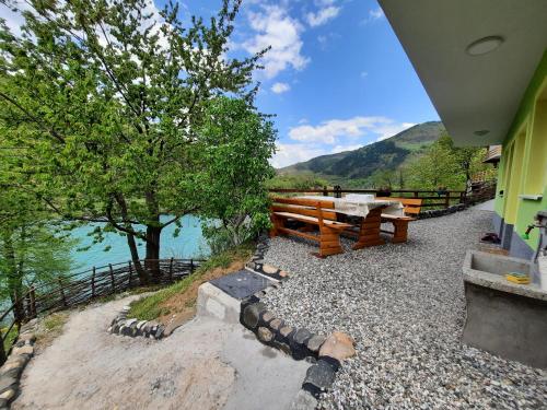 a picnic table and a bench next to the water at Apartmani Vila na Drini in Foča