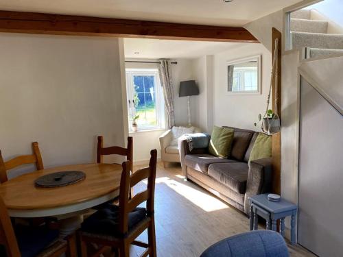 a living room with a table and a couch at Coombe Cottage in Honiton