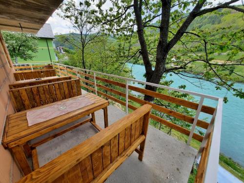 a wooden bench on a balcony with a view of the water at Apartmani Vila na Drini in Foča