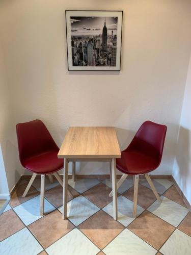 a table and two red chairs in a waiting room at 1-Zimmer-Wohnung Astfeld in Langelsheim
