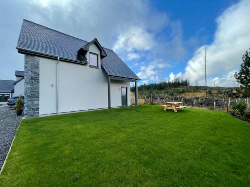 a white building with a picnic table in a yard at Little Thistle Apartment in Whitebridge