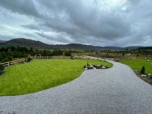 a gravel road leading to a green field with mountains at Little Thistle Apartment in Whitebridge