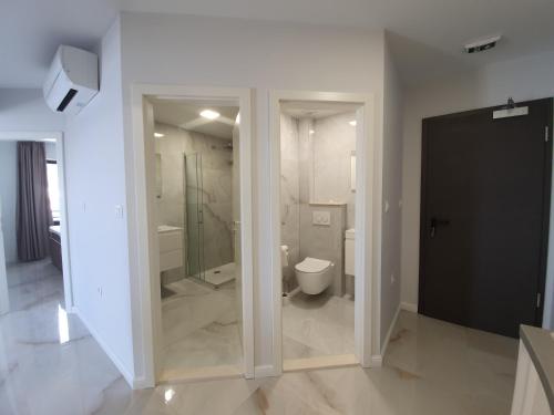 a bathroom with a toilet and a glass shower at Bellissima Apartments in Brist
