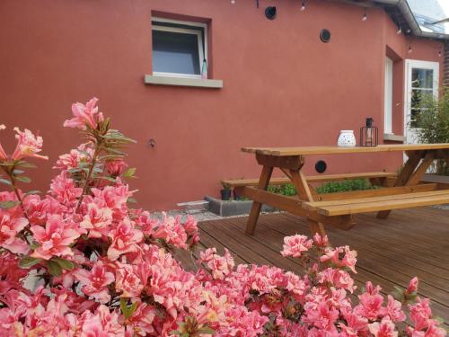 a picnic table and pink flowers in front of a building at Chez le Petit Peintre in Laboissière-en-Thelle