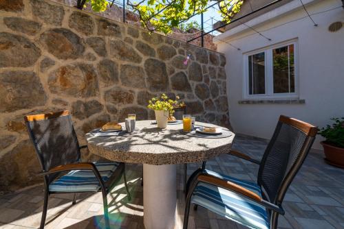 a table and chairs on a patio with a stone wall at Apartment Ruzica in Dubrovnik