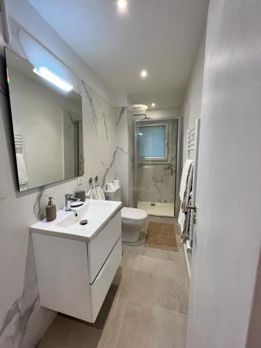 a white bathroom with a sink and a toilet at Le MACA 1 in Le Cannet