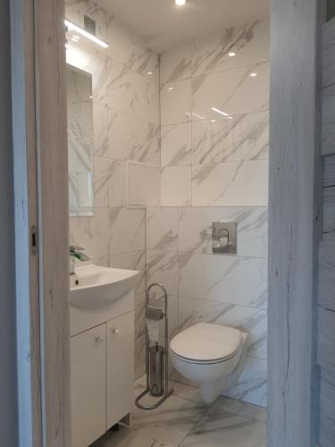 biała łazienka z toaletą i umywalką w obiekcie Mieszkanie 1.1 z widokiem na morze w Gdańsku